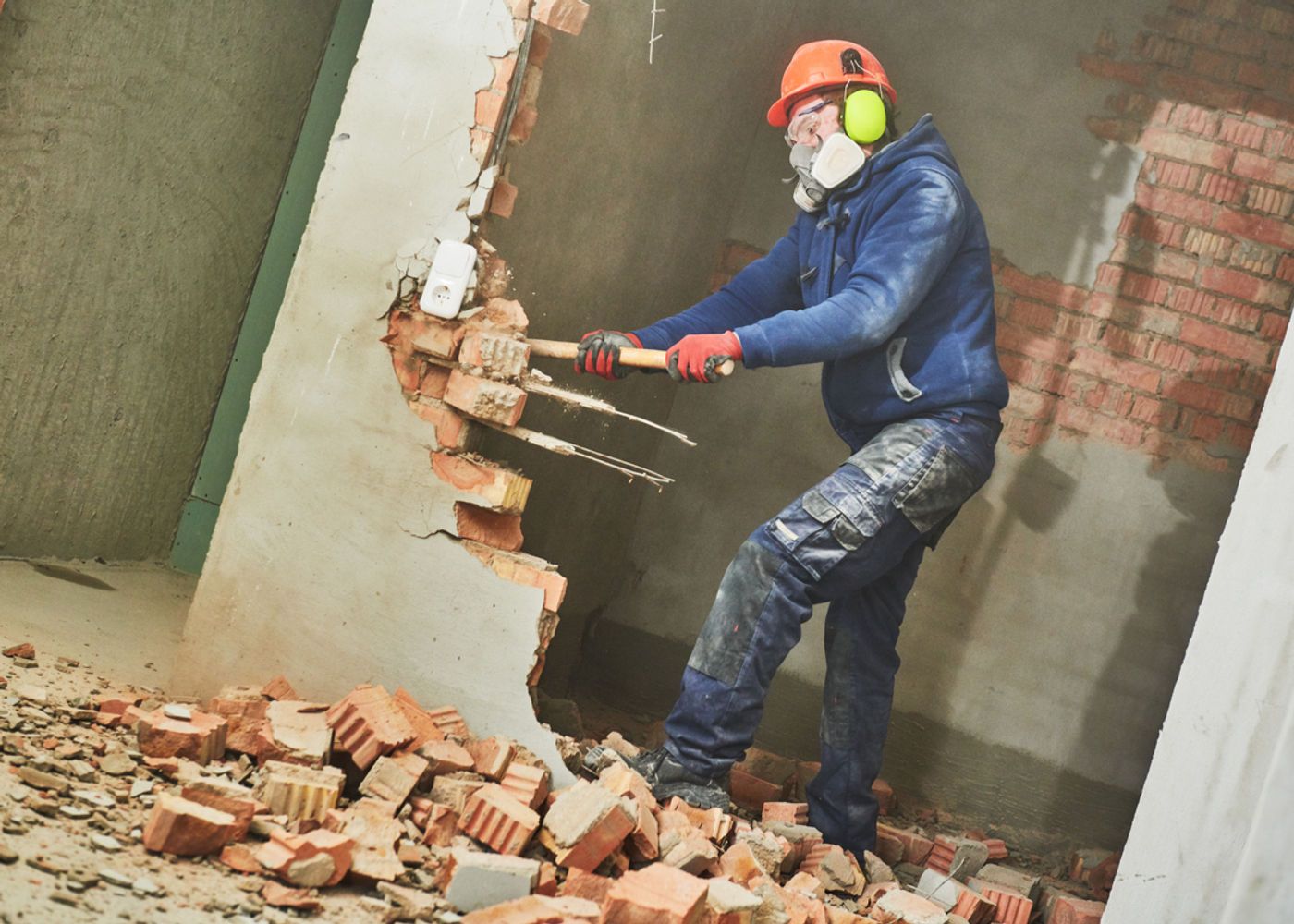 Ouvrier de Renova en démolition d'un mur de brique